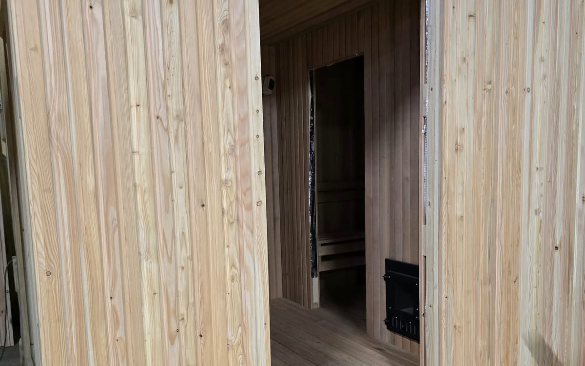 Sauna interior being fitted out: panelled wall and door opening